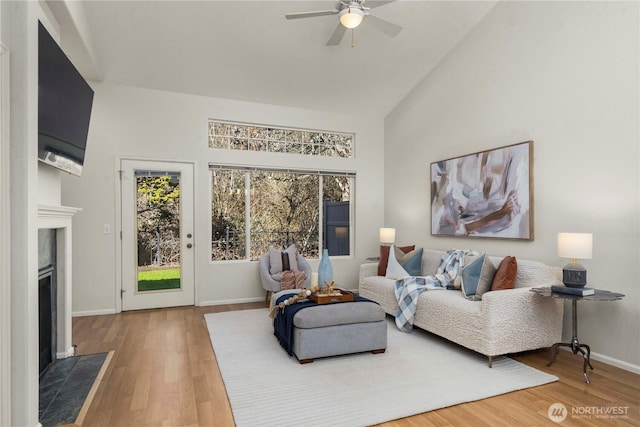 living room with wood finished floors, plenty of natural light, a fireplace with flush hearth, and baseboards