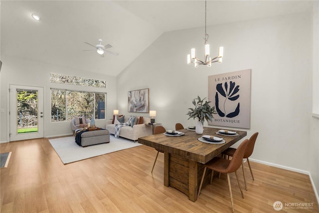 dining area featuring light wood-style floors, baseboards, high vaulted ceiling, and ceiling fan with notable chandelier