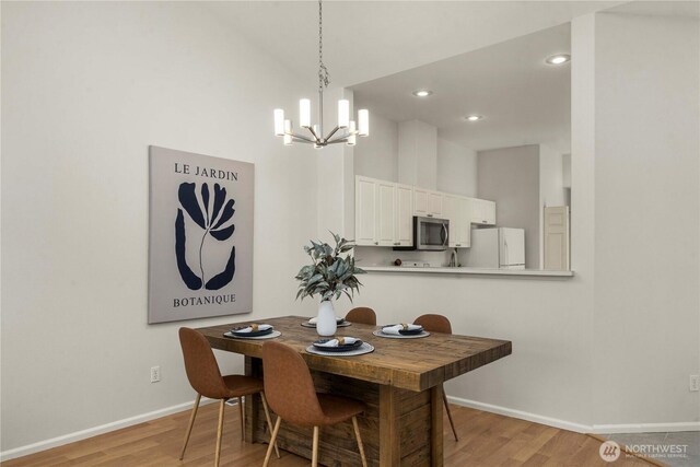 dining room with light wood finished floors, a high ceiling, and baseboards