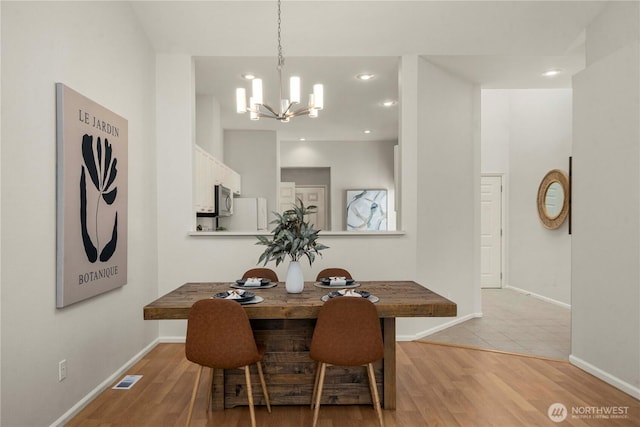 dining area featuring light wood-style flooring, visible vents, and baseboards