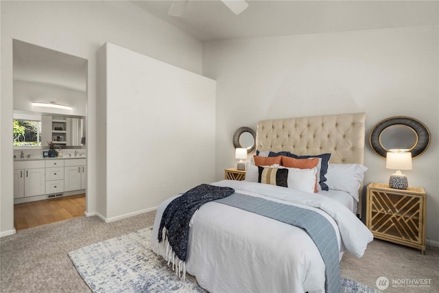 bedroom featuring light colored carpet, visible vents, ensuite bathroom, a sink, and baseboards