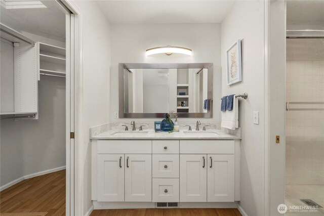 full bath with a stall shower, a sink, and double vanity