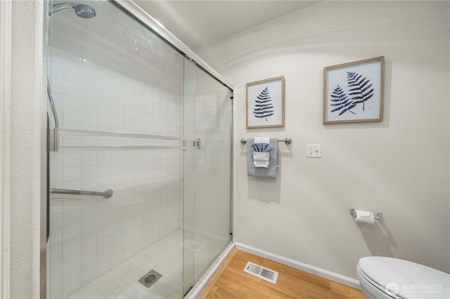 full bath featuring toilet, a shower stall, visible vents, and wood finished floors