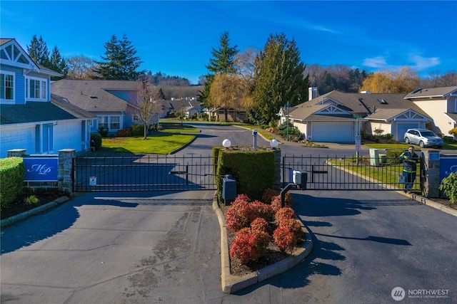 view of road featuring a residential view, a gate, curbs, and a gated entry