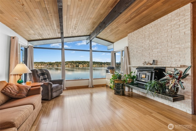 sunroom with wood ceiling, lofted ceiling with beams, a wood stove, and a water view