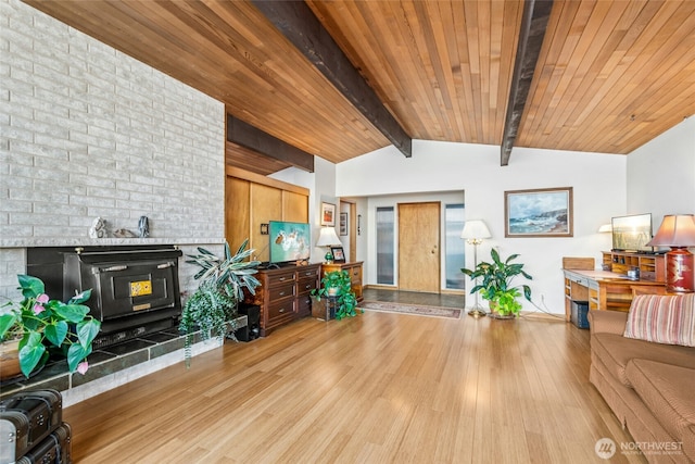 living room with light wood finished floors, wood ceiling, vaulted ceiling with beams, and a wood stove