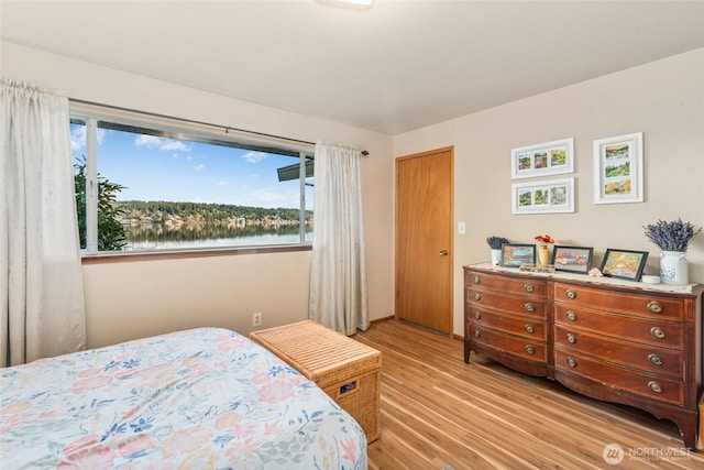 bedroom with a water view and light wood finished floors