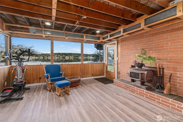 sunroom / solarium featuring a wood stove and a water view