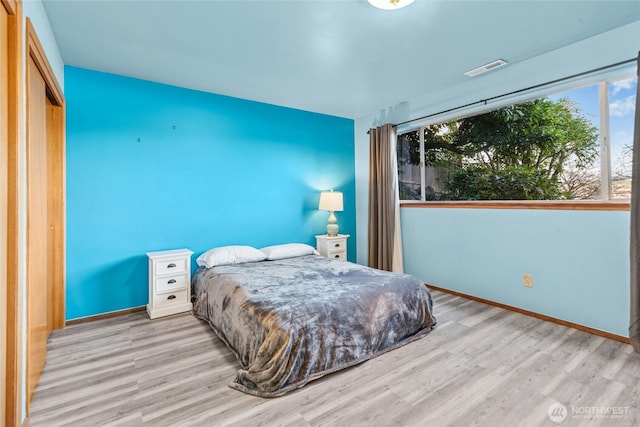 bedroom featuring visible vents, baseboards, and wood finished floors