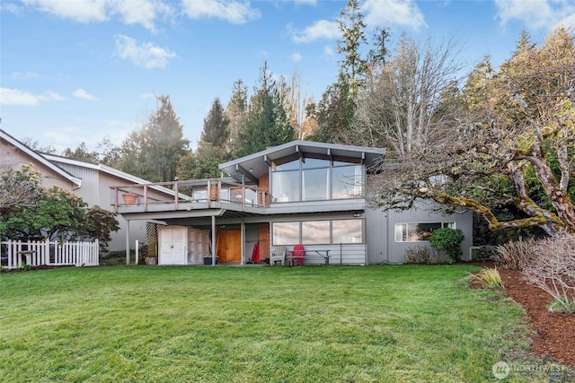 back of property featuring a lawn, a deck, and fence