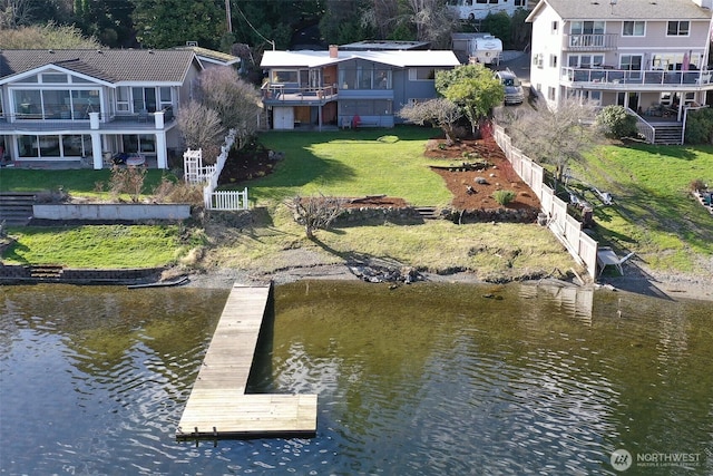 view of dock with fence, a yard, and a water view