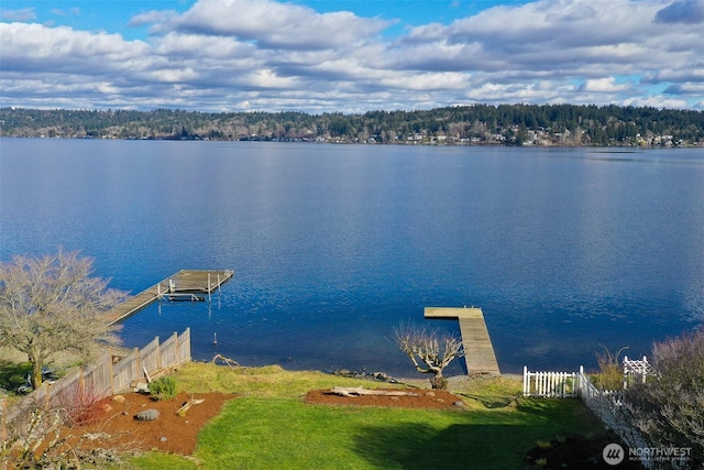 water view with a forest view, fence, and a floating dock