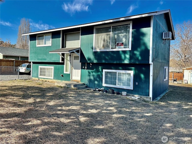 split foyer home with an AC wall unit and fence