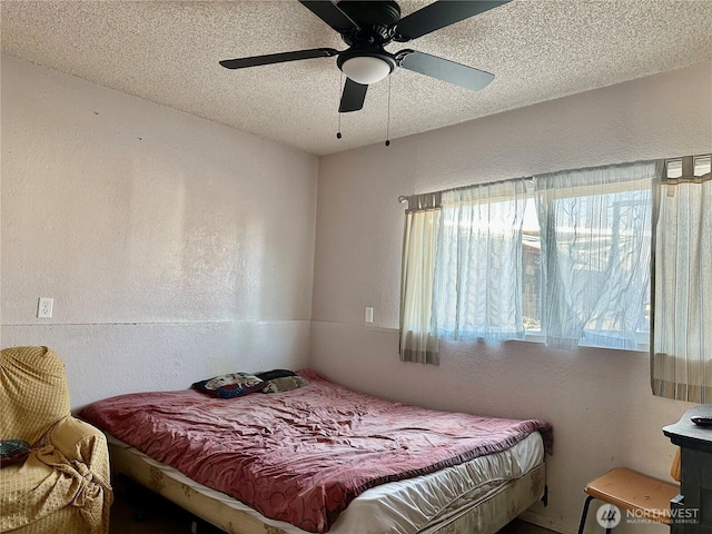 bedroom with a ceiling fan, a textured wall, and a textured ceiling