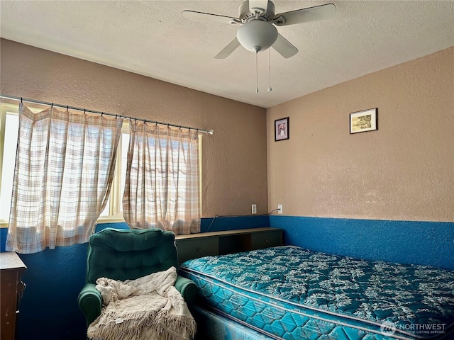 bedroom with a textured wall, a textured ceiling, and ceiling fan