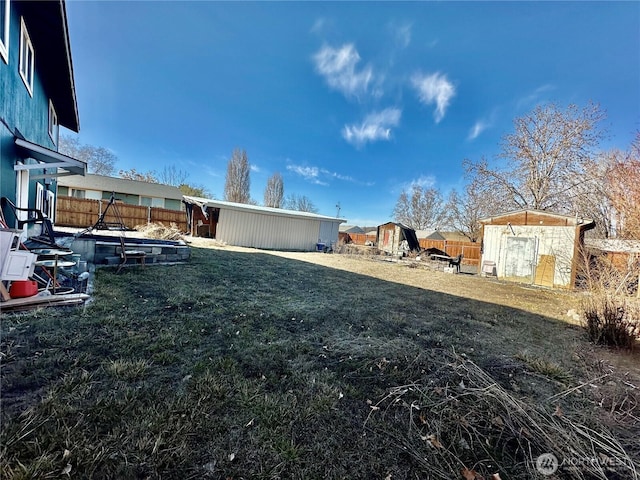 view of yard featuring a fenced backyard, a storage unit, and an outbuilding