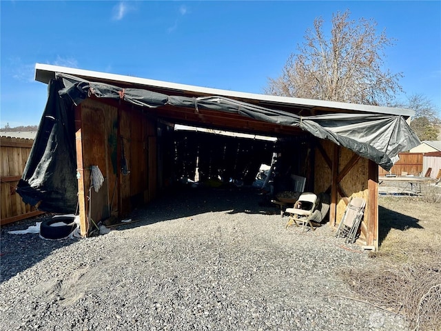 exterior space featuring gravel driveway, fence, and a carport