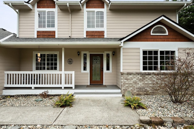 view of front of house featuring a porch, brick siding, and a shingled roof