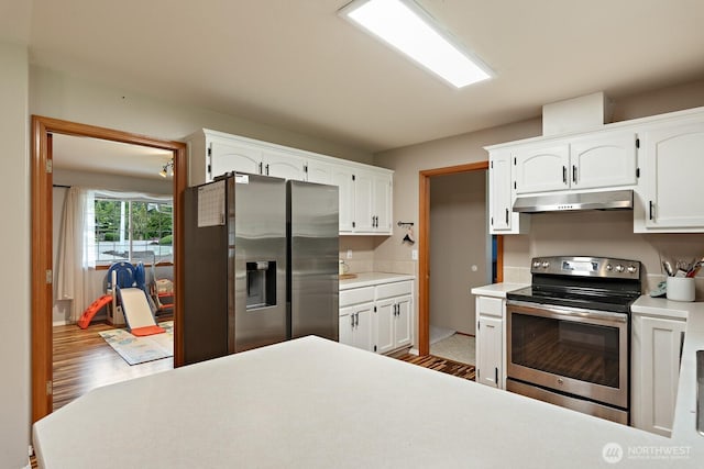 kitchen with under cabinet range hood, light countertops, stainless steel appliances, wood finished floors, and white cabinetry