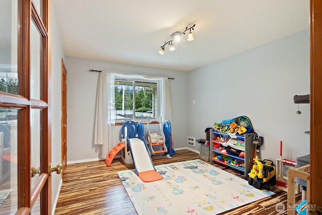 game room featuring rail lighting, wood finished floors, and baseboards