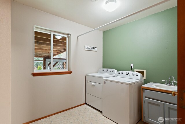 laundry area featuring baseboards, light floors, separate washer and dryer, cabinet space, and a sink