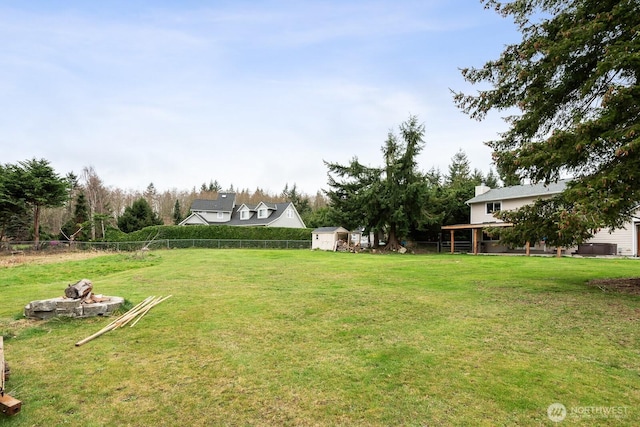 view of yard with a storage shed, an outdoor structure, and fence