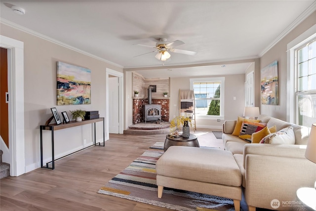 living area with a wood stove, ornamental molding, and wood finished floors