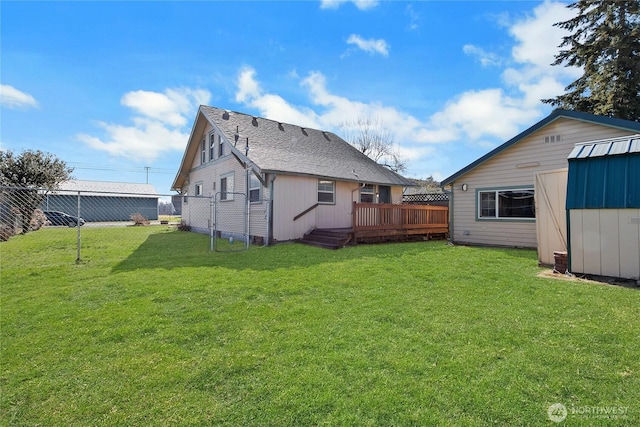 rear view of house featuring a deck, a fenced backyard, a storage shed, an outdoor structure, and a yard