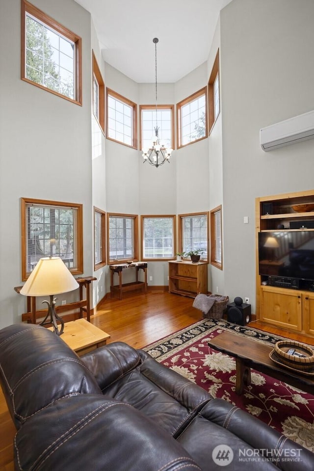 living area with an AC wall unit, wood finished floors, and a chandelier