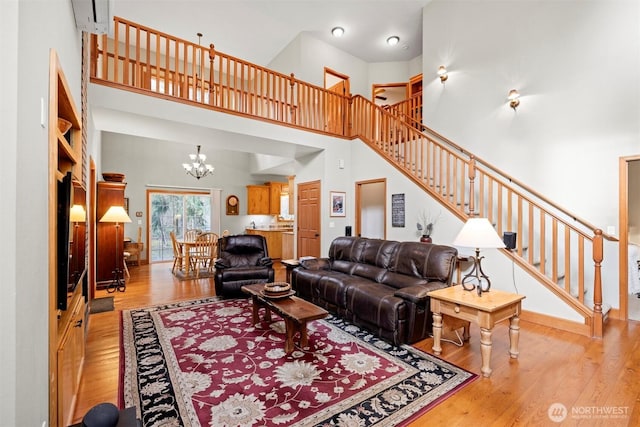 living area with a notable chandelier, stairway, a towering ceiling, and wood-type flooring