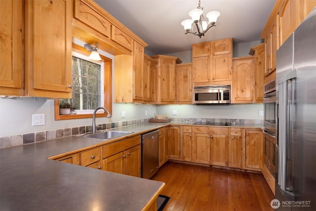 kitchen with pendant lighting, a sink, dark wood-style floors, stainless steel appliances, and an inviting chandelier