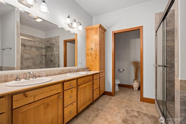 bathroom with a sink, toilet, a stall shower, and double vanity