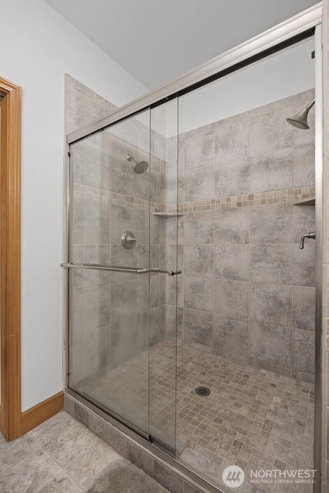 bathroom with tile patterned floors, baseboards, and a stall shower