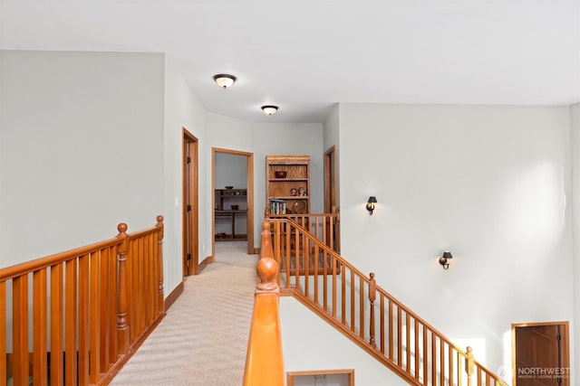 hall featuring an upstairs landing, baseboards, and light carpet