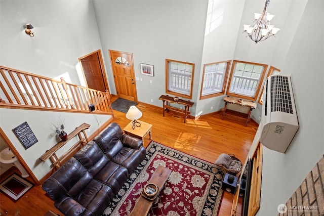 living area with baseboards, wood finished floors, stairs, a towering ceiling, and an inviting chandelier