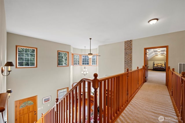 corridor with an inviting chandelier, an upstairs landing, light colored carpet, and visible vents