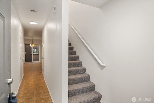 stairs featuring a chandelier and baseboards