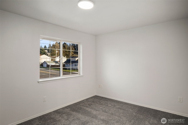 empty room featuring baseboards and dark colored carpet