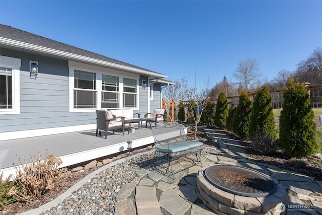 view of patio featuring an outdoor fire pit, fence, and a deck