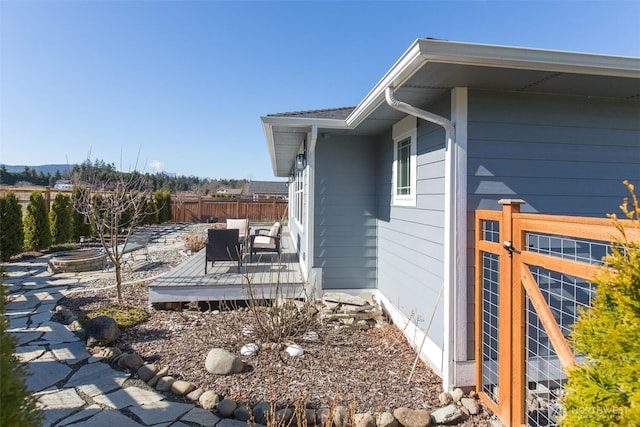 view of side of home featuring a fire pit, fence, and a deck