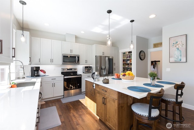 kitchen with stainless steel appliances, a breakfast bar, a sink, a center island, and dark wood finished floors