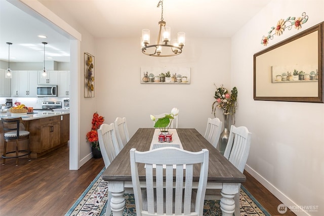 dining space with dark wood-type flooring, baseboards, and an inviting chandelier