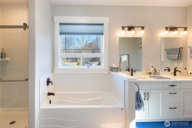 full bath featuring a stall shower, double vanity, a sink, and a bath