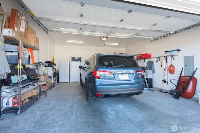 garage with electric panel, freestanding refrigerator, and a garage door opener