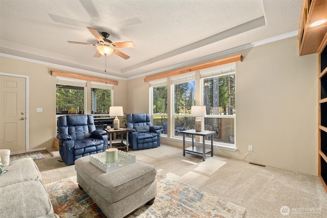 living area featuring a tray ceiling, visible vents, ornamental molding, and carpet flooring