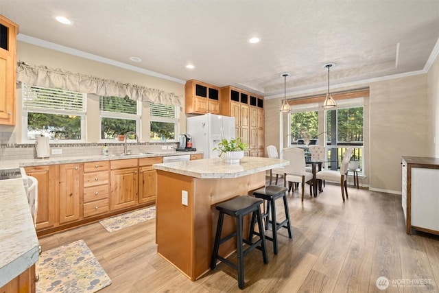 kitchen featuring white appliances, a center island, light wood-type flooring, and ornamental molding