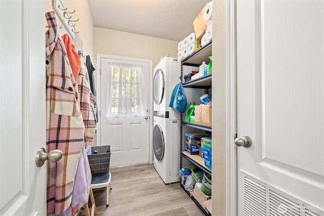 laundry area with laundry area, stacked washer / dryer, and light wood-style floors