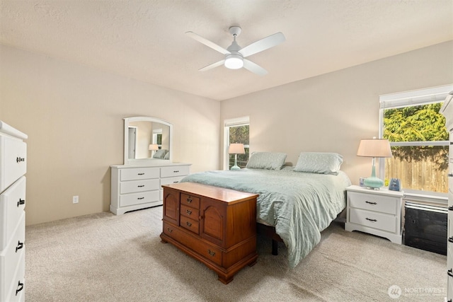 bedroom featuring multiple windows, light colored carpet, and ceiling fan