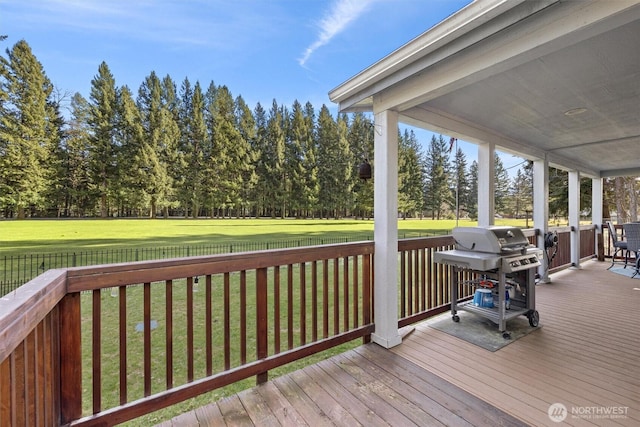 deck with a lawn, a grill, and a fenced backyard