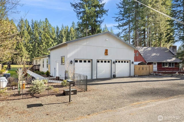 view of front facade featuring an outdoor structure, fence, a garage, and driveway